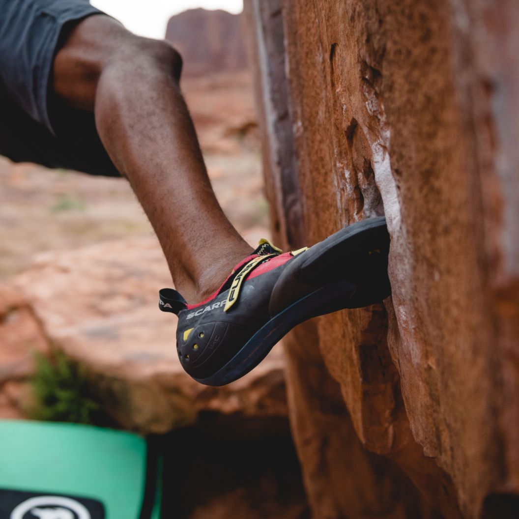 Man Climbing on Rock with climbing shoes on and pad underneath of him