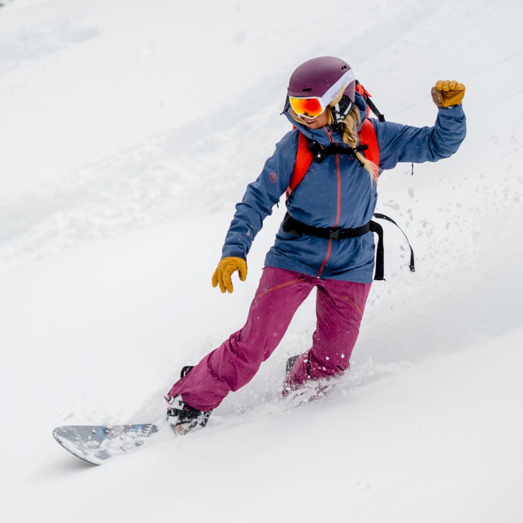 Girl snowboarding down a snowy mountain
