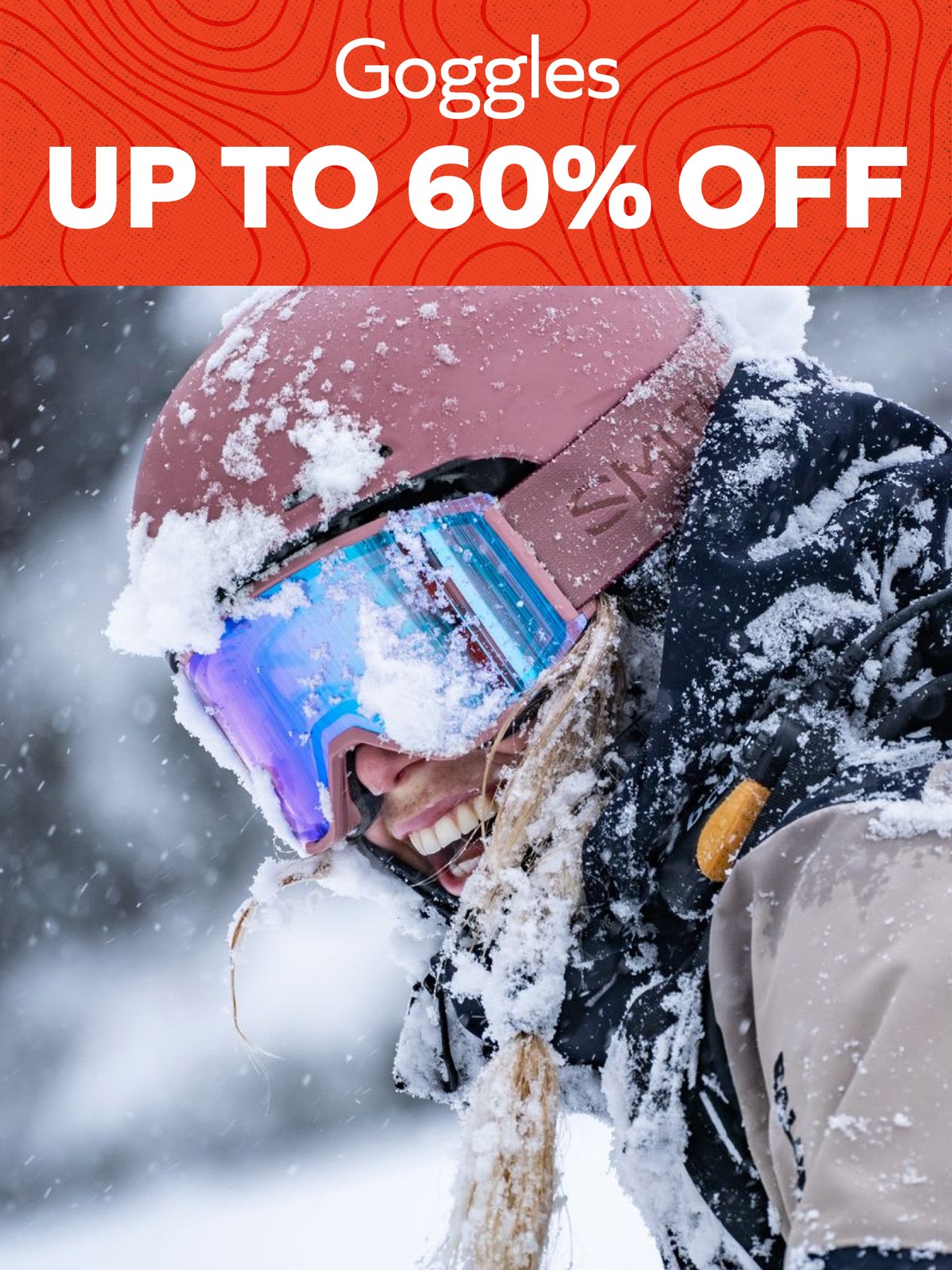 Goggles up to 60% off — smiling skier in a snow-covered helmet and mirrored goggles during a snowfall.