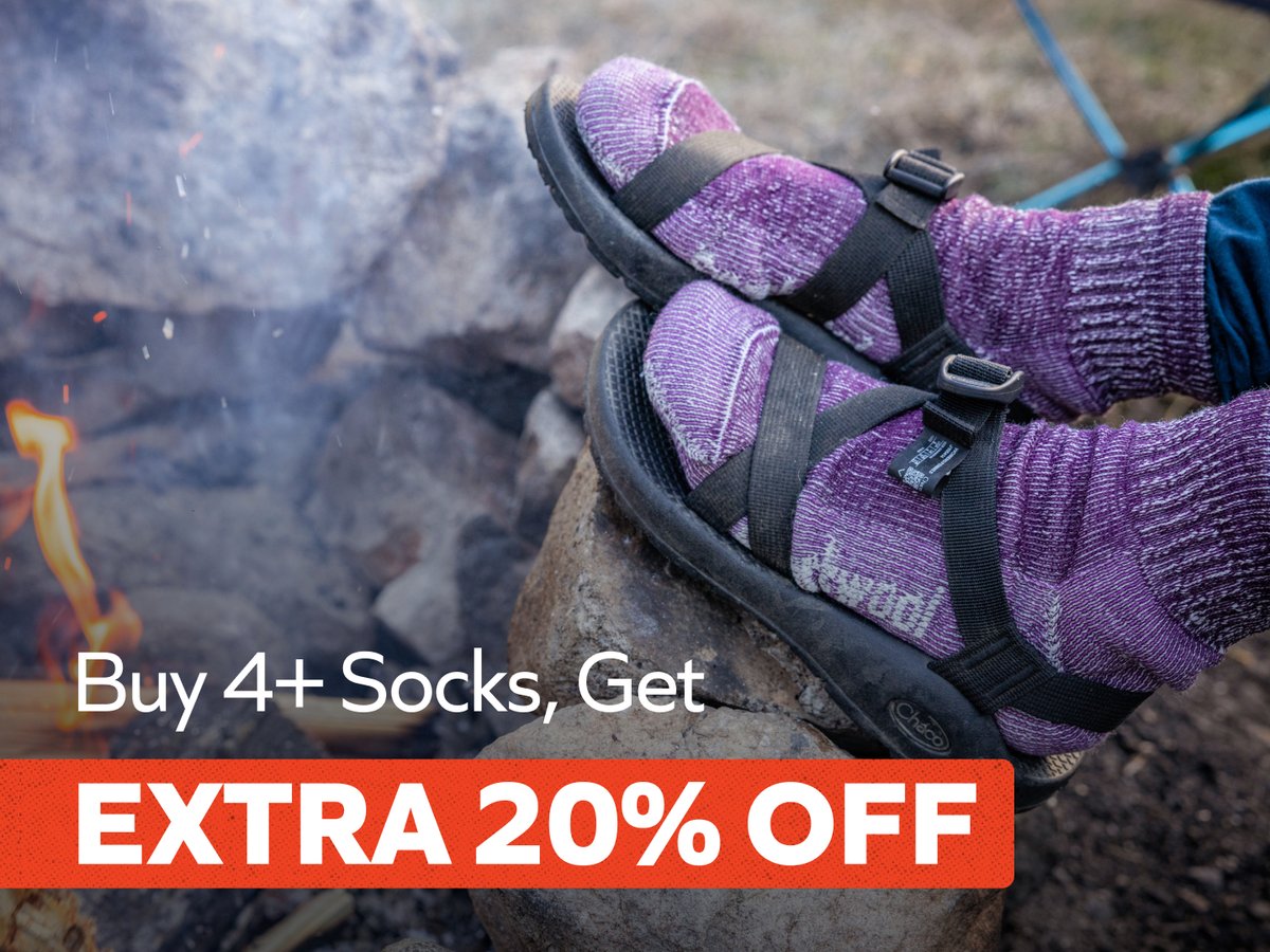 Purple wool socks worn with black strappy sandals by a campfire, with an offer for extra 20% off when you buy 4+ socks.