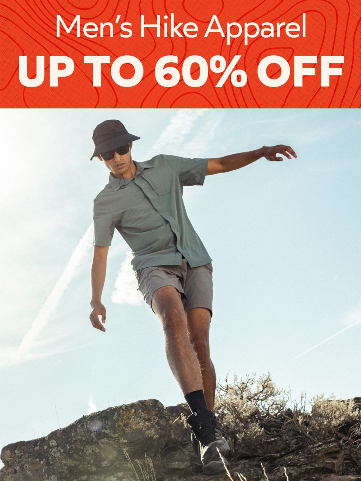 Up to 60% off Men's Hike Apparel — hiker in green shirt and cap jumping on rocky ridge